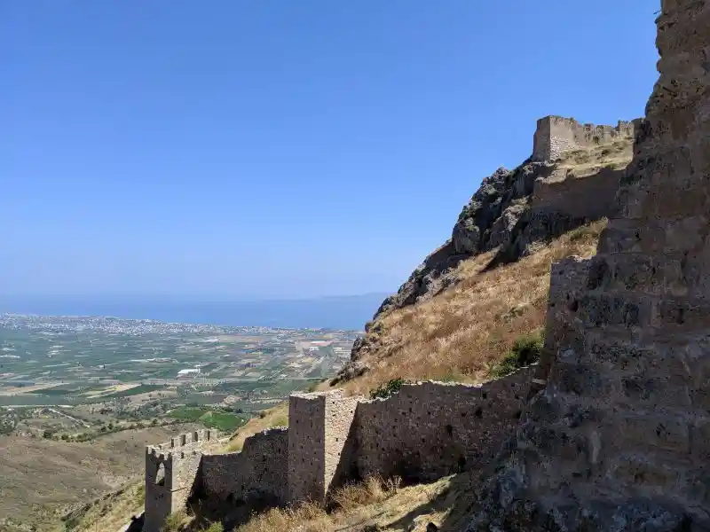 Multi-layered defensive walls and towers of Acrocorinth fortress climbing the steep mountainside above the Corinthian plain